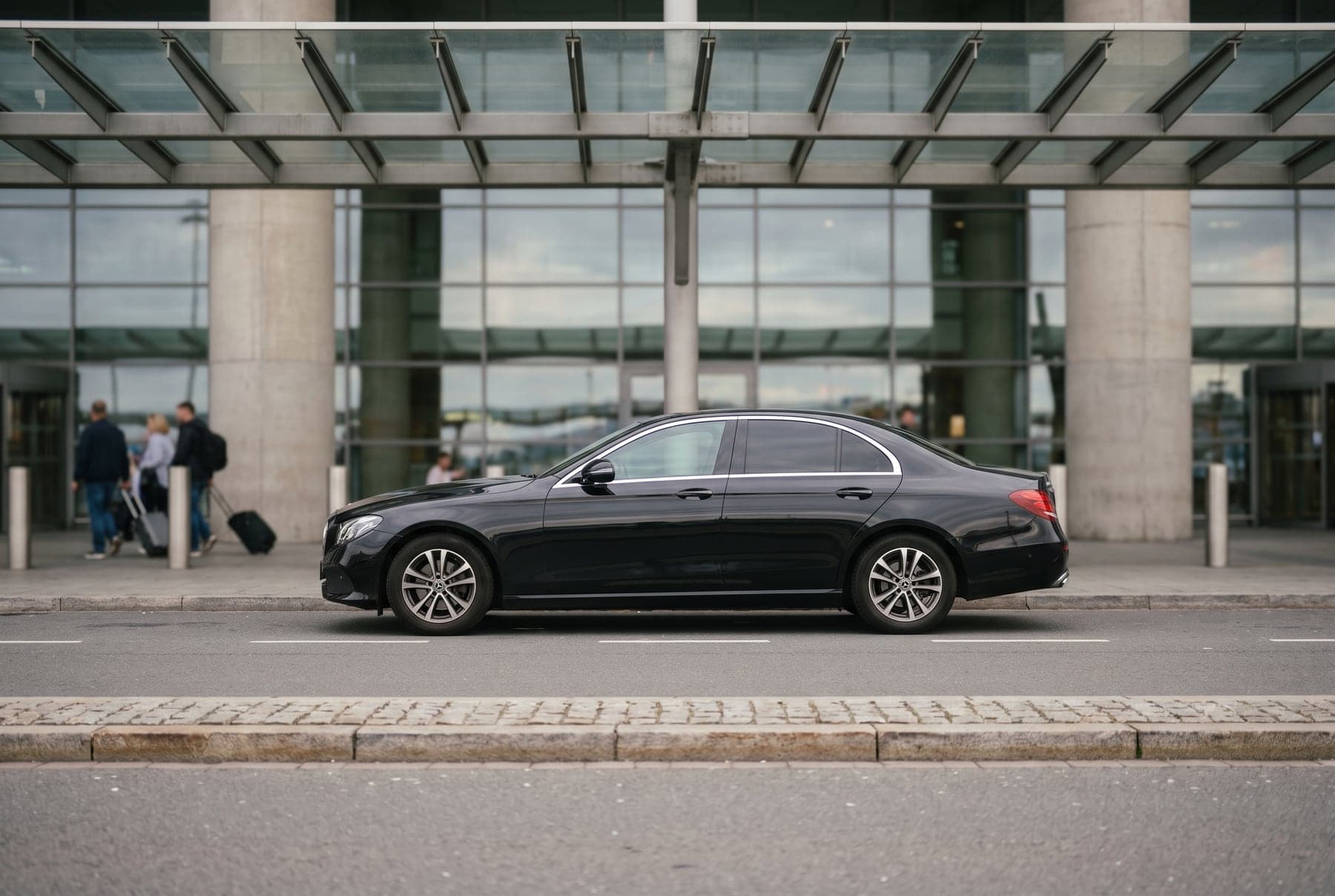 Berlina negra estacionada frente a una terminal de aeropuerto